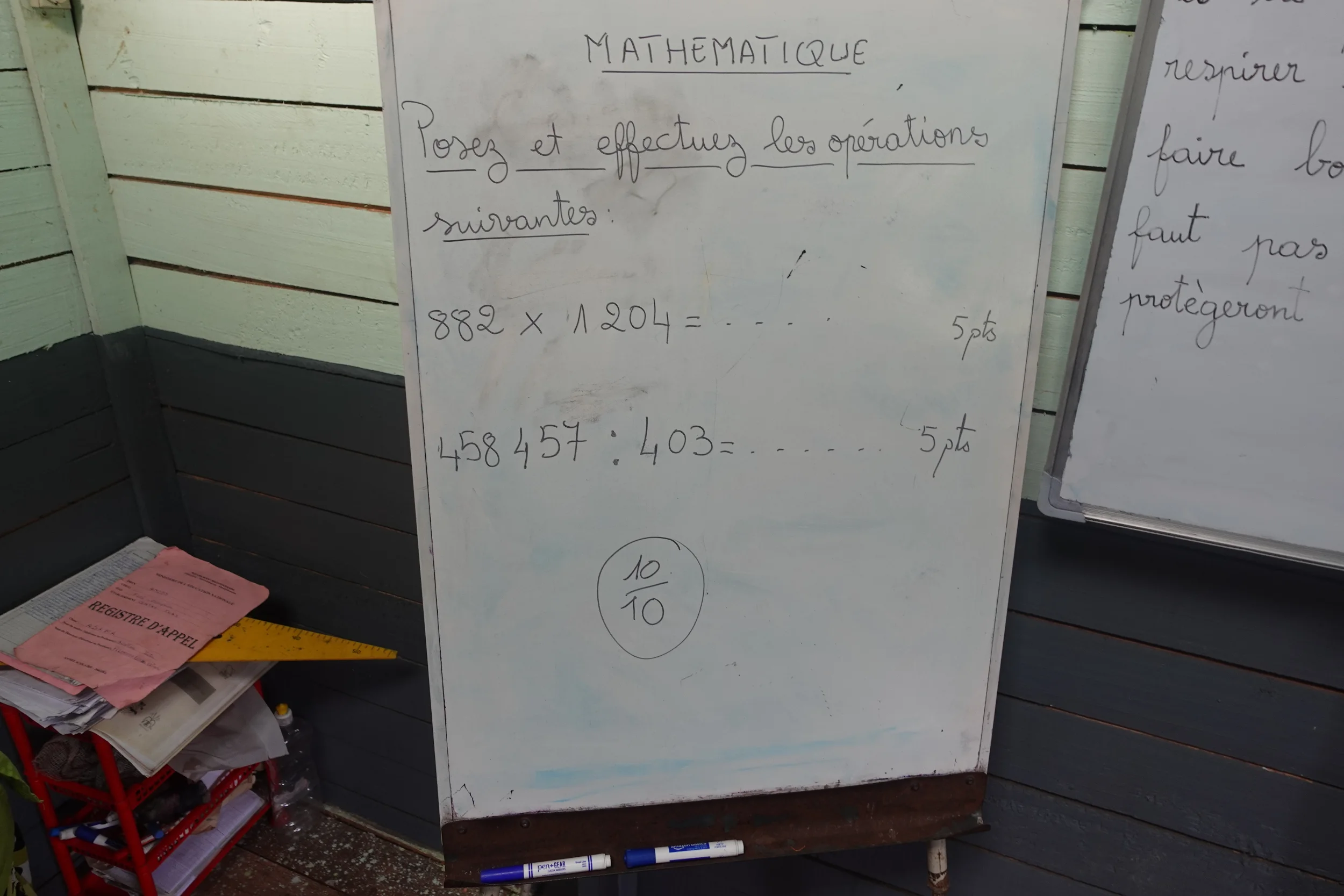 Whiteboard with multiplication and division exercises, graded ten out of ten