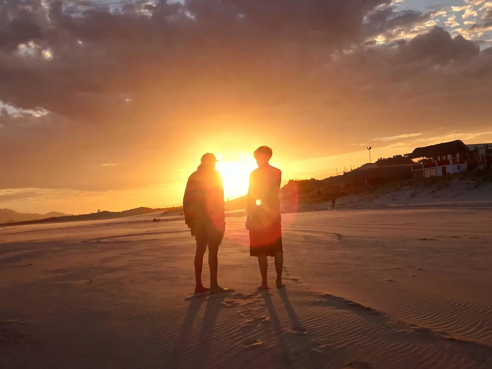 Two silhouettes watching the sunset on the beach in Fort Dauphin